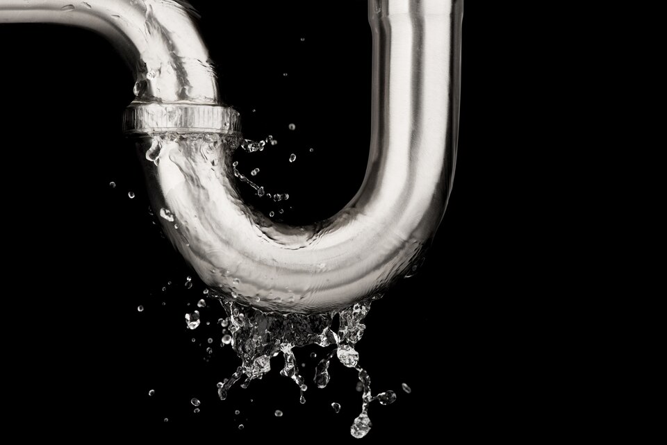 Water splashing from a curved metal pipe against a black background