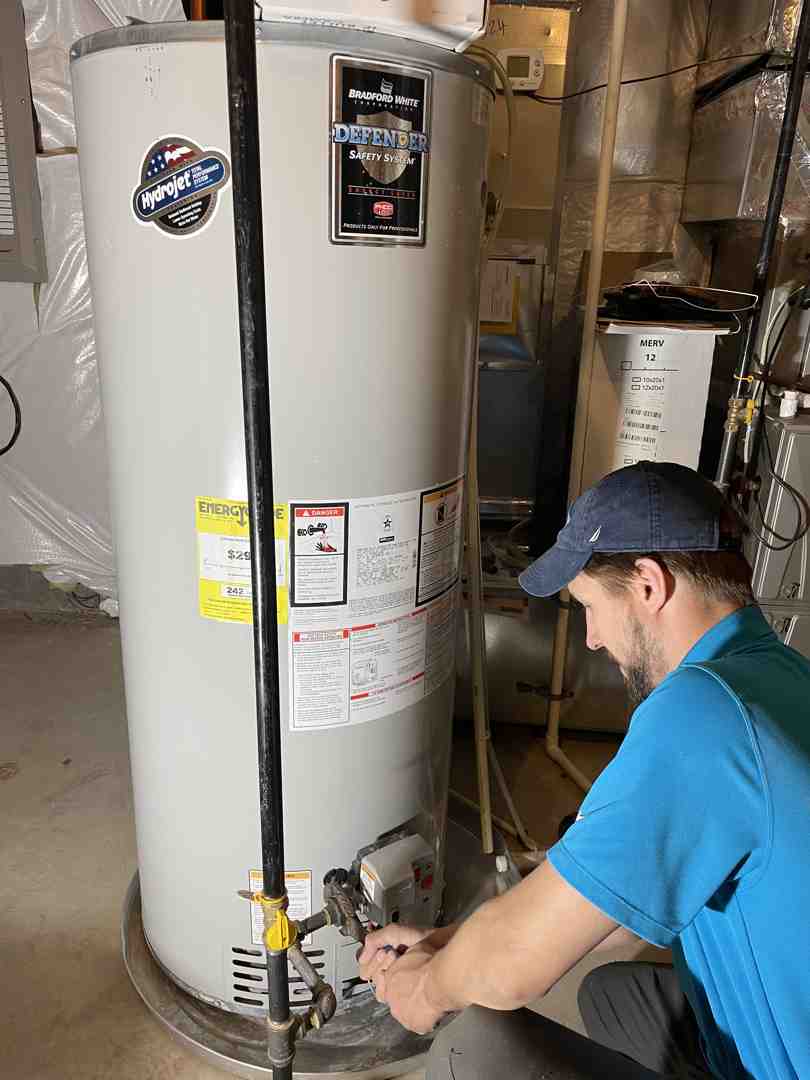 Technician in blue shirt repairing a Bradford White water heater