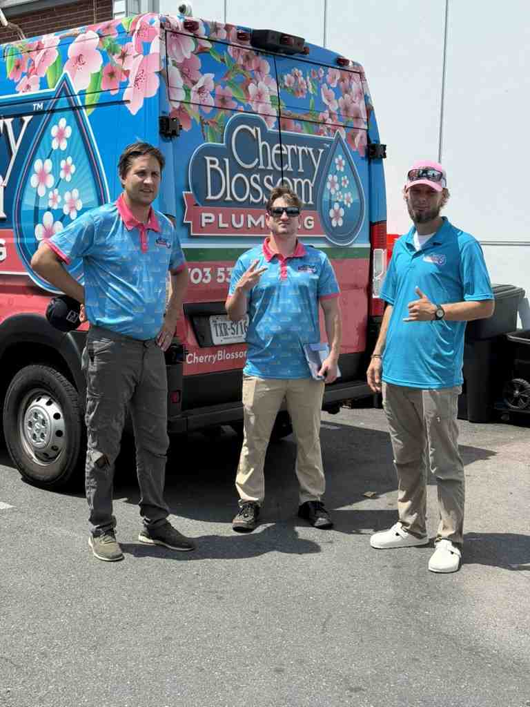 Three plumbers standing in front of a Cherry Blossom Plumbing van