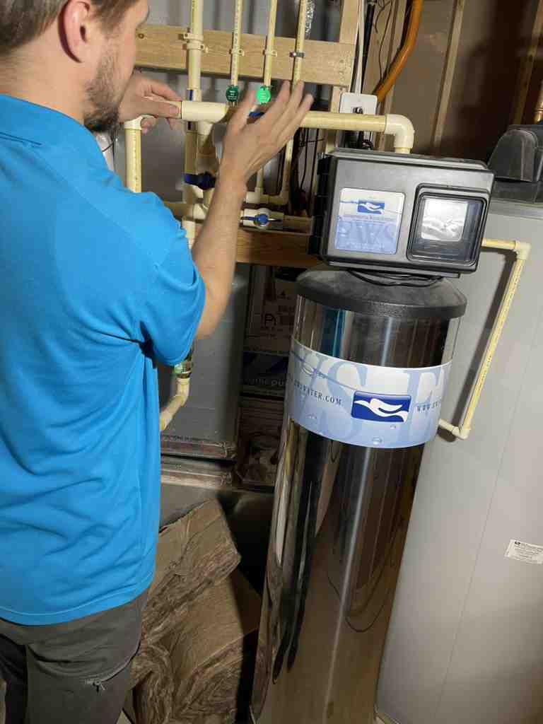 Technician adjusting water filtration system in mechanical room
