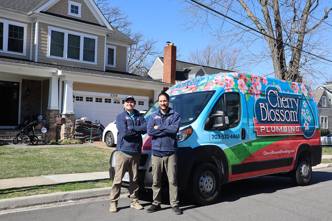 Two plumbers standing next to colorful Cherry Blossom Plumbing van