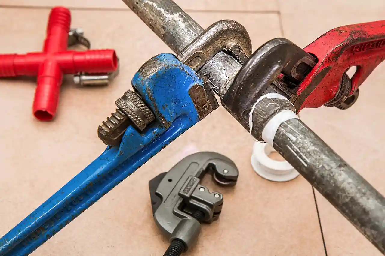 Pipe wrenches and plumbing tools on a wooden surface