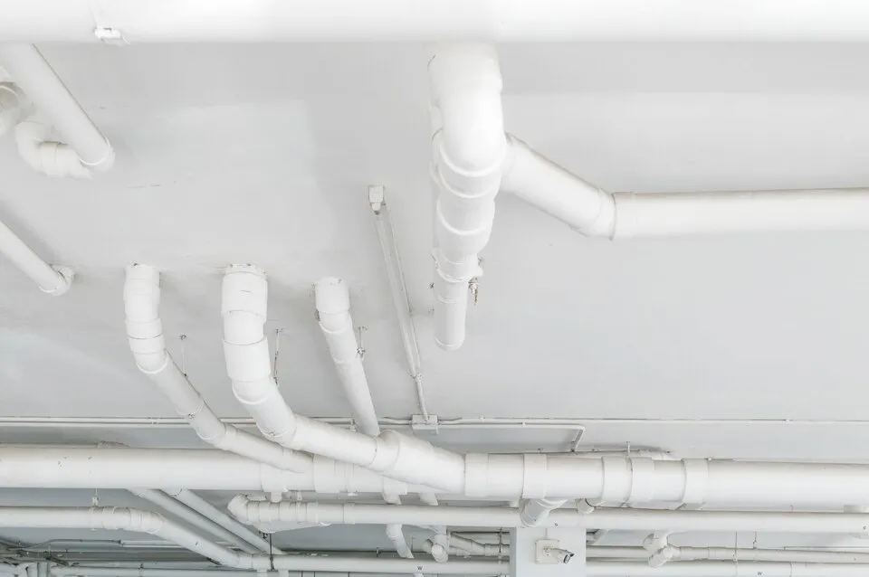 White pipes and plumbing network on a ceiling or industrial space