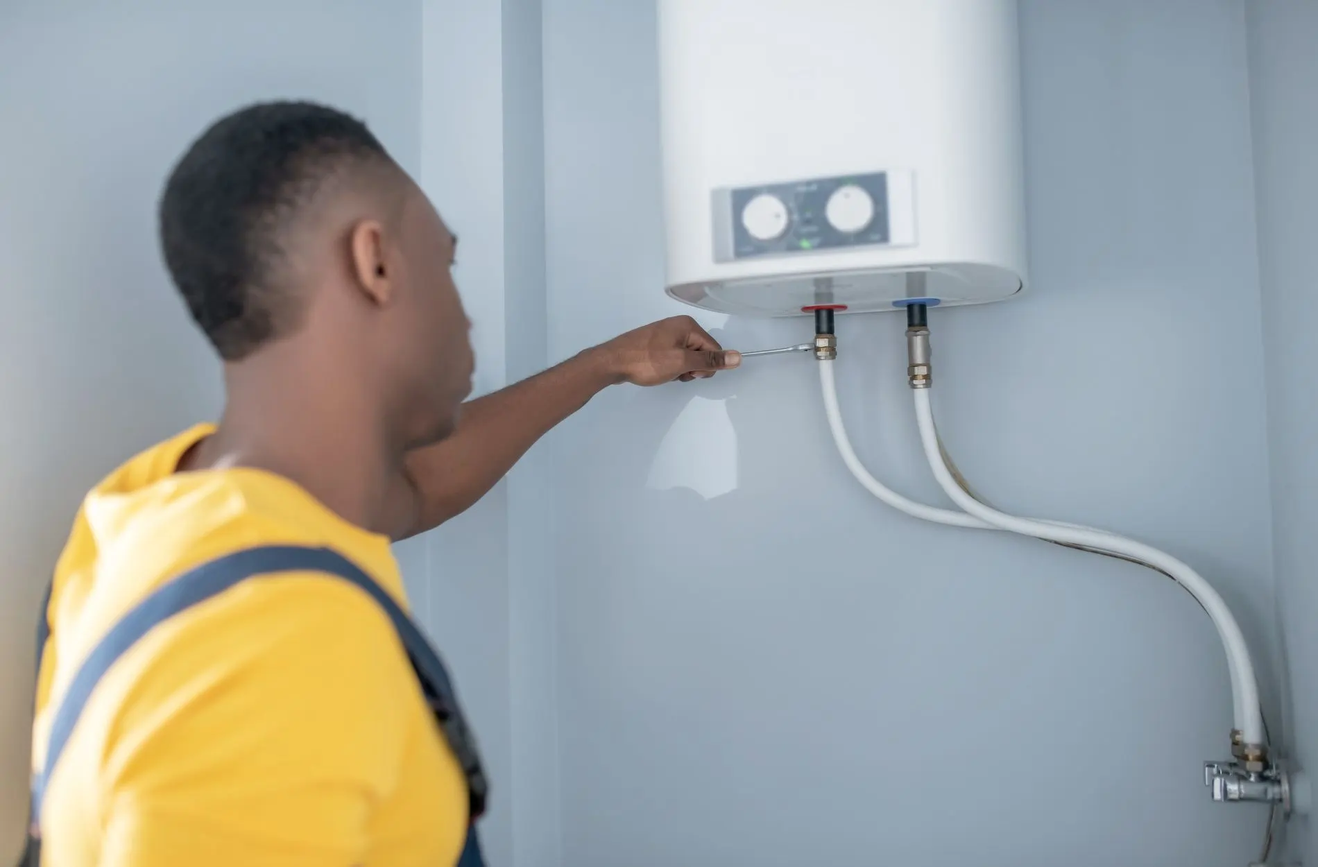 Technician in yellow vest checking water heater connections