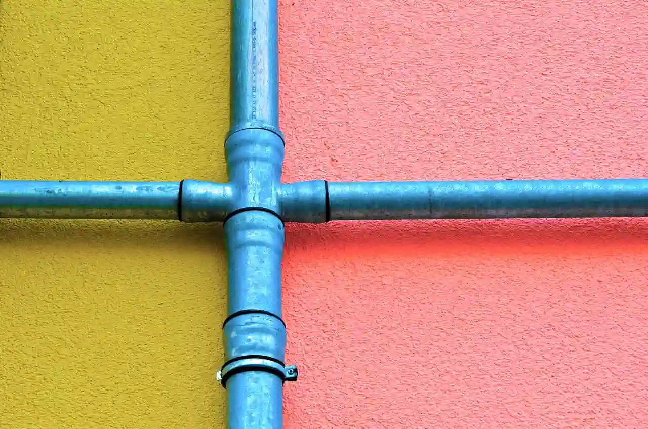 Blue metal pipes intersecting on yellow and pink textured walls
