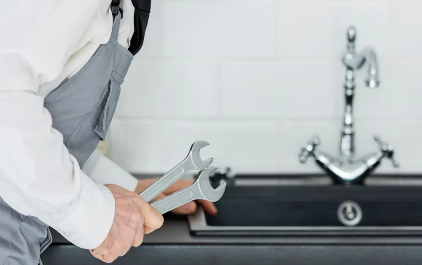 Worker holding wrench near industrial machinery with robotic arm