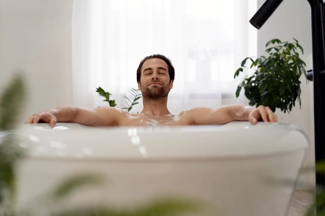 Person relaxing with eyes closed in a bathtub surrounded by plants