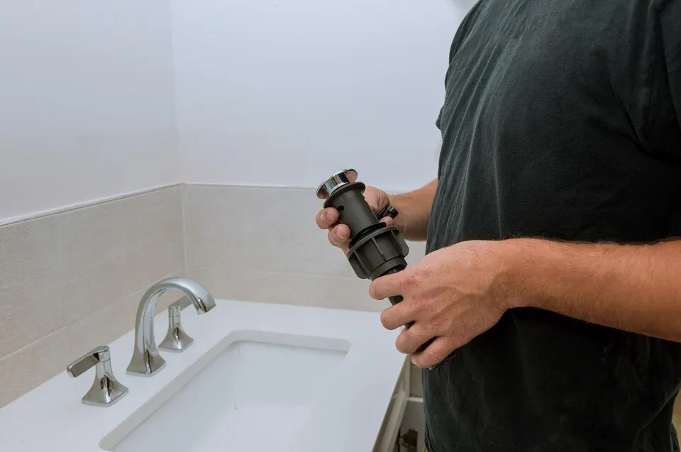 Hand holding metal water filter near bathroom sink