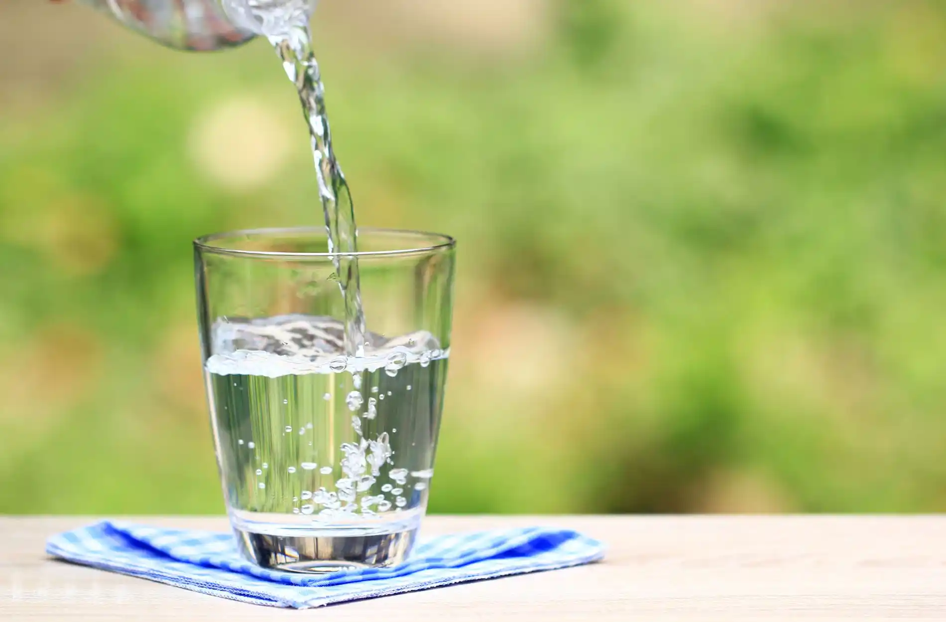 Clear water pouring into a glass on a blue and white napkin