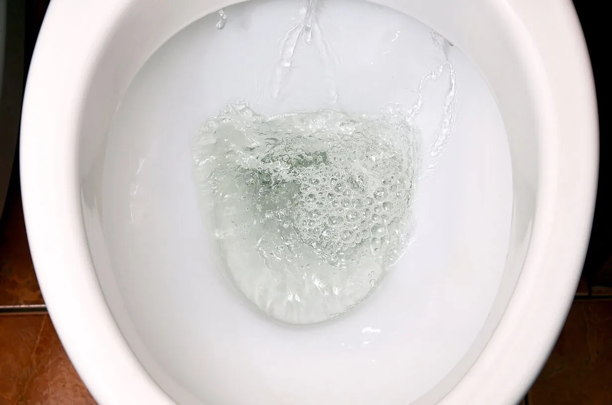 Water flushing inside a white toilet bowl with bubbles and splashing
