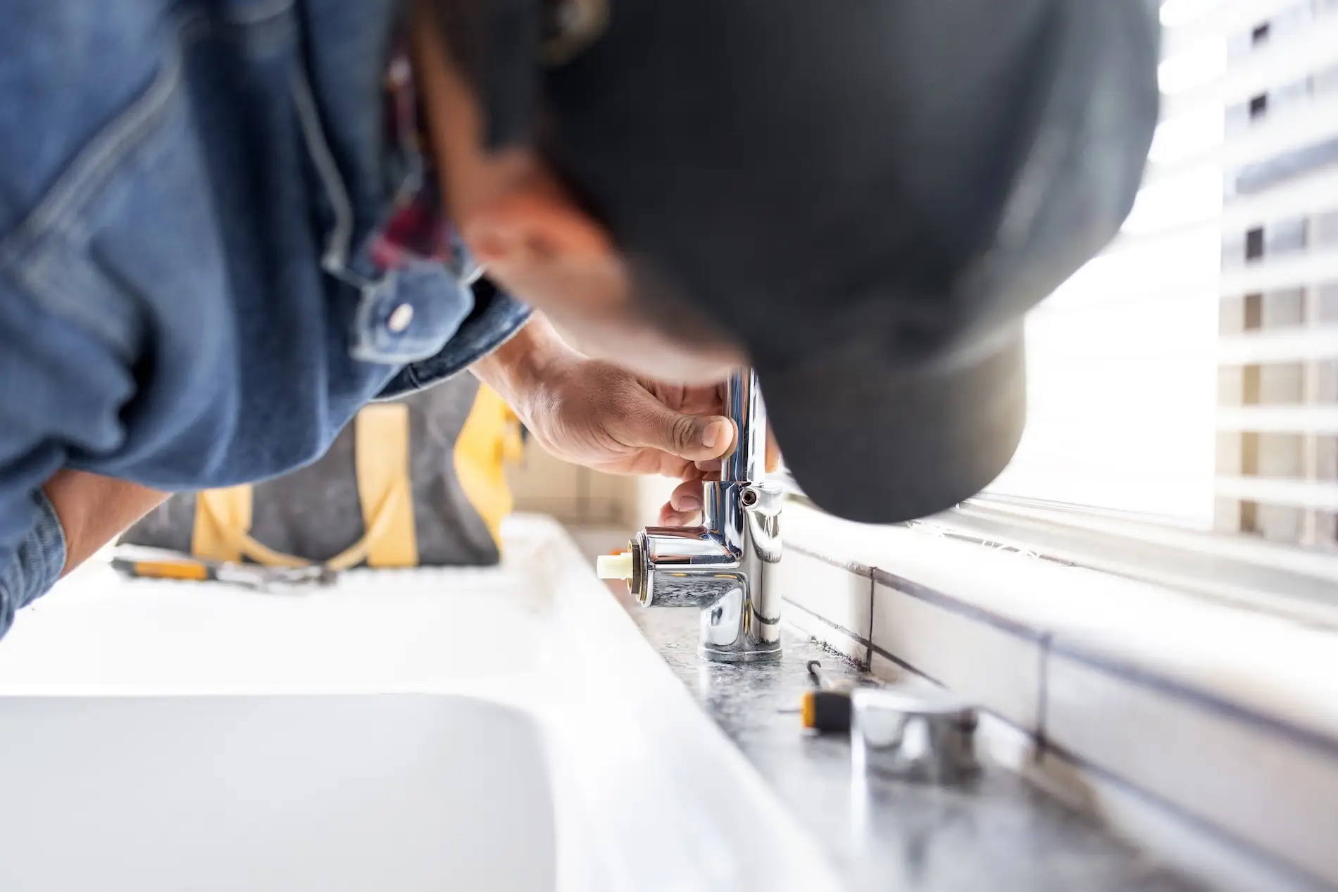 Plumber installing or repairing chrome faucet in bathroom or kitchen