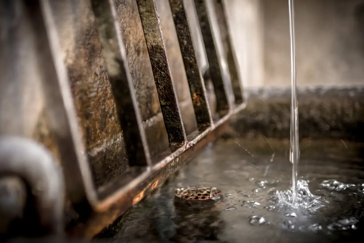 Water dripping near rusty metal bars with small object in foreground