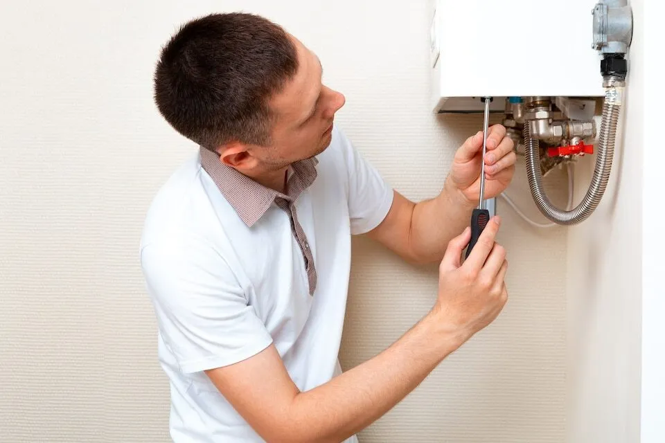 Technician fixing water heater pipes with a screwdriver