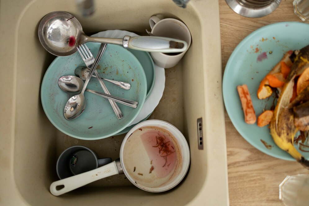 Dirty dishes and utensils in a sink after a meal with roasted vegetables