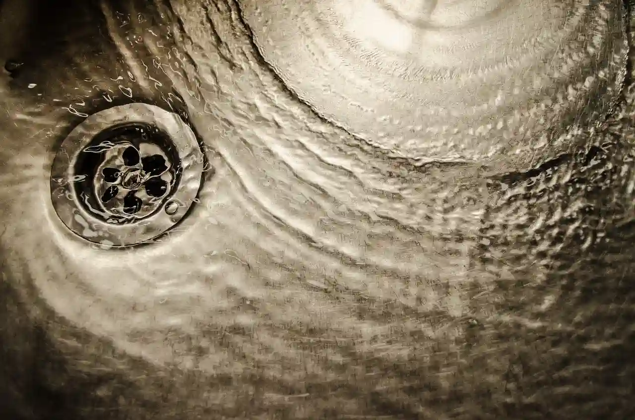 Textured surface with swirling drain and water droplets in sepia tone