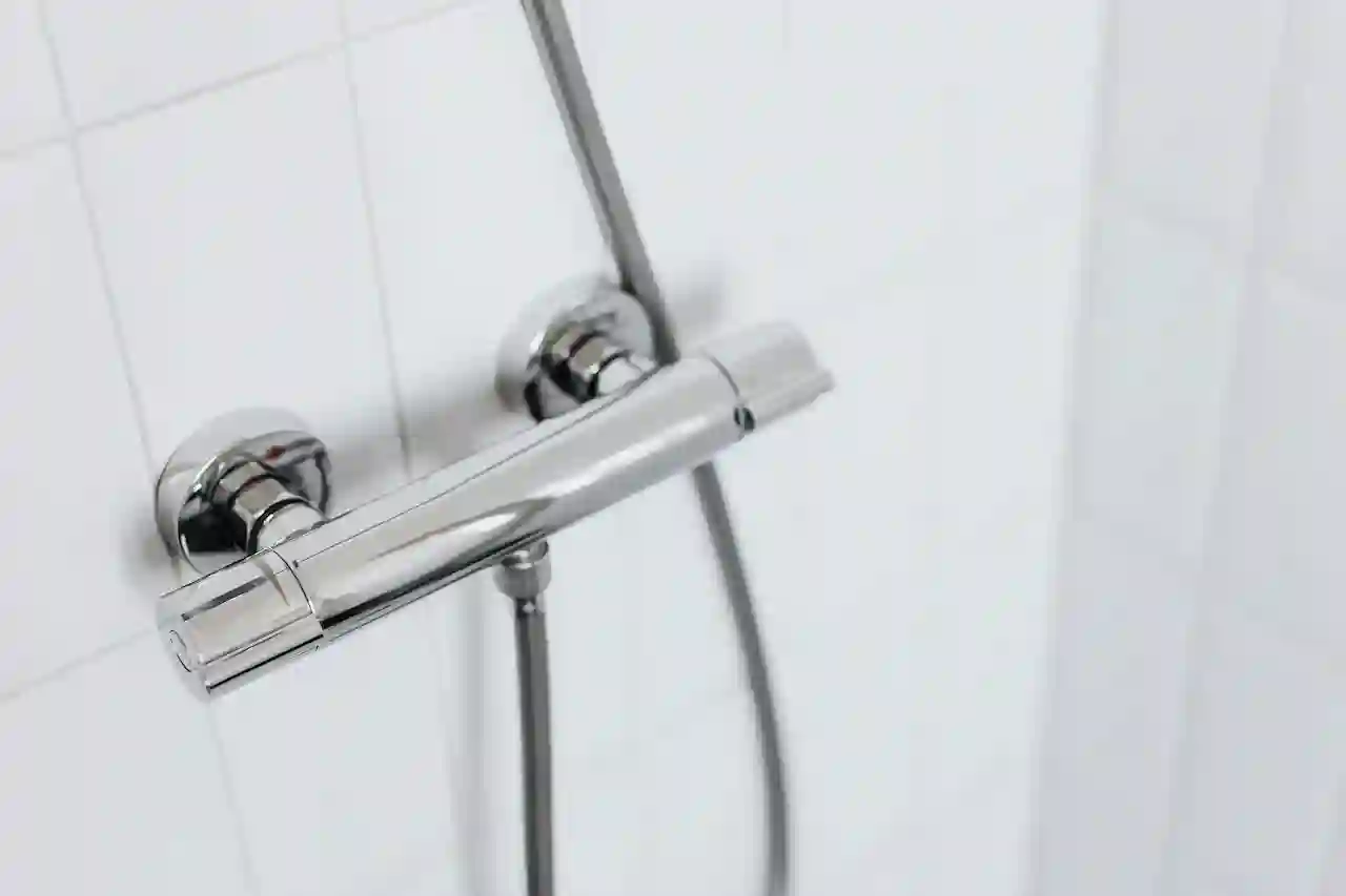 Modern chrome shower fixture on white tiled bathroom wall