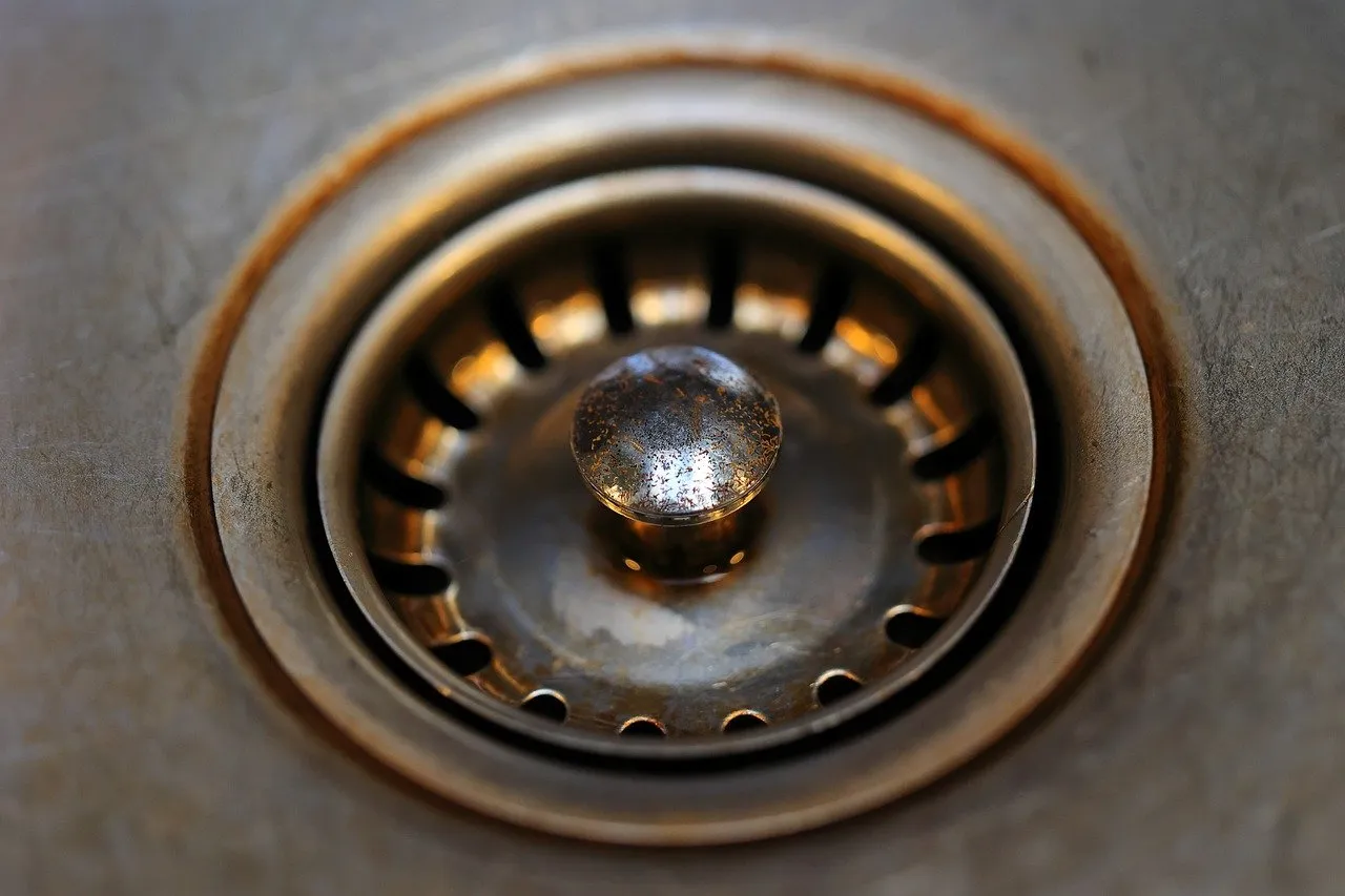 Rusty kitchen sink drain with circular metal strainer in close-up