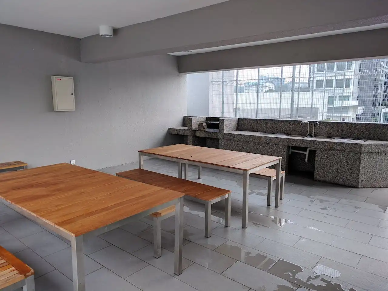 Minimalist kitchen area with wooden tables, benches, and granite countertop