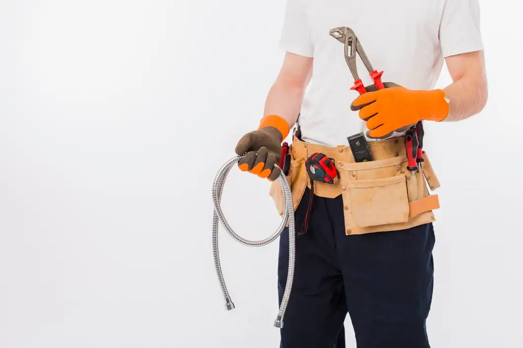 Technician with tool belt and flexible metal hose wearing orange gloves