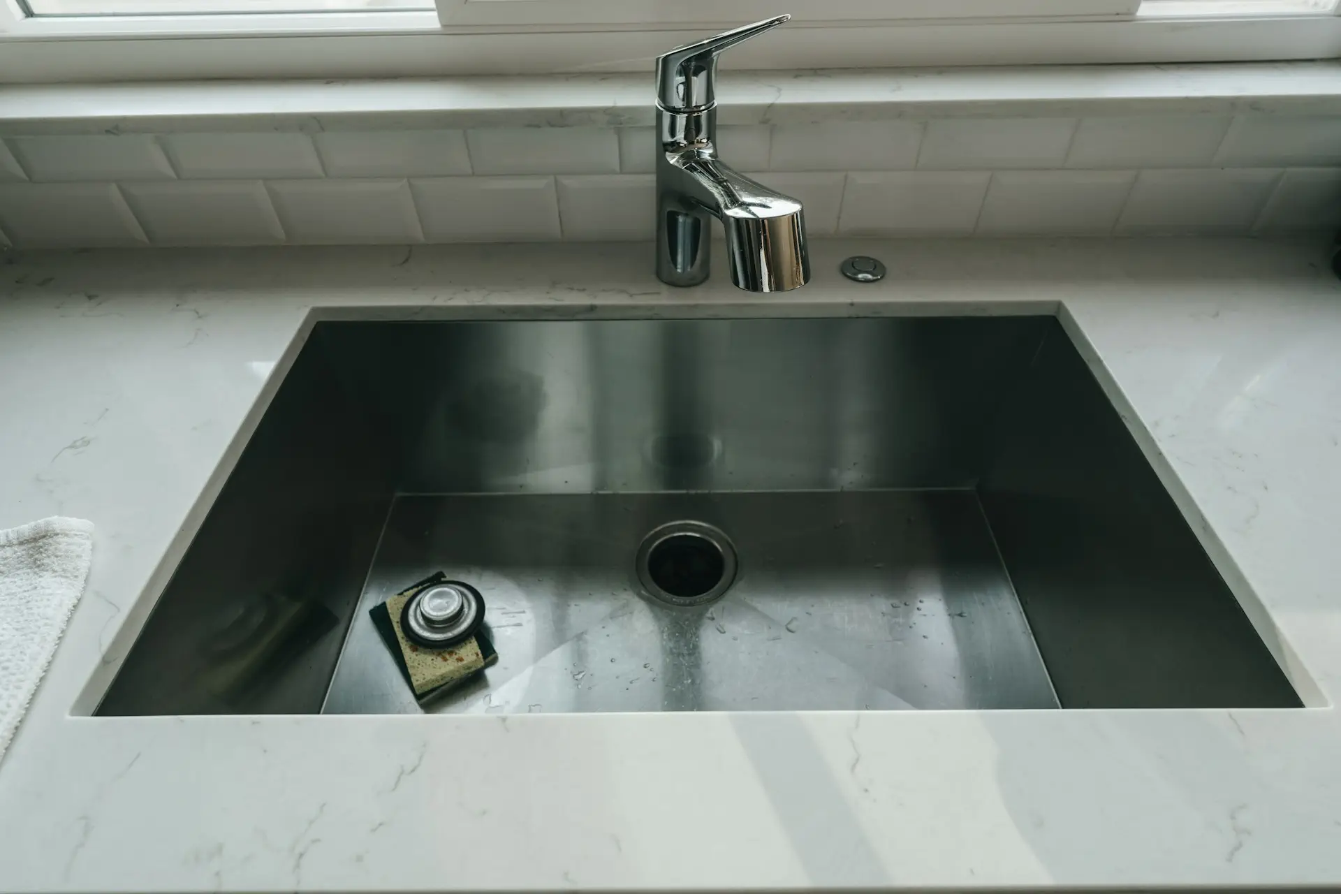 Modern stainless steel kitchen sink with chrome faucet and soap dish