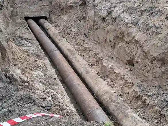 Two large pipes laid in an excavated trench with rocky soil