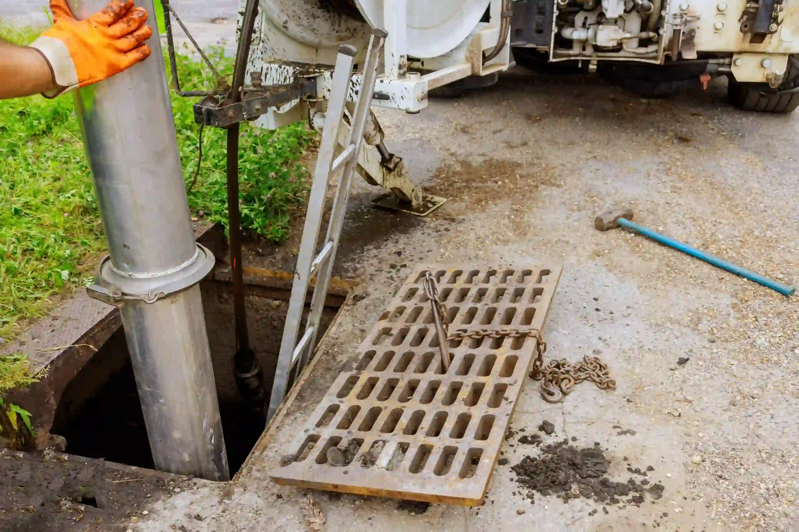 Construction site with drainage grate, machinery, and orange gloved hand