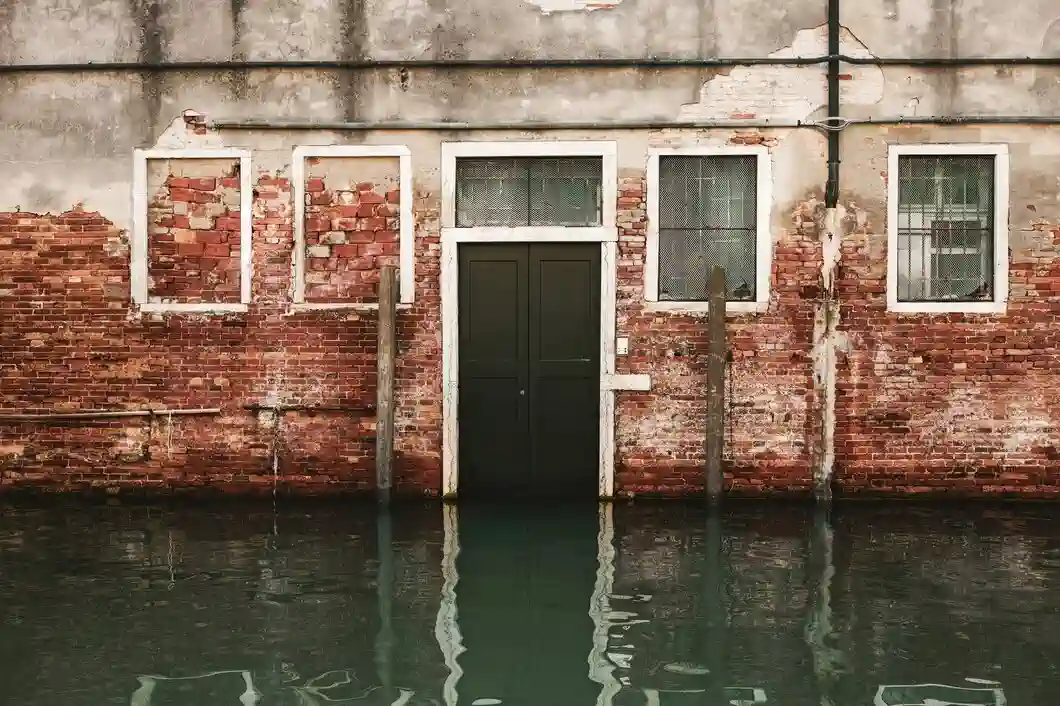 Weathered brick building with door and windows partially submerged in water