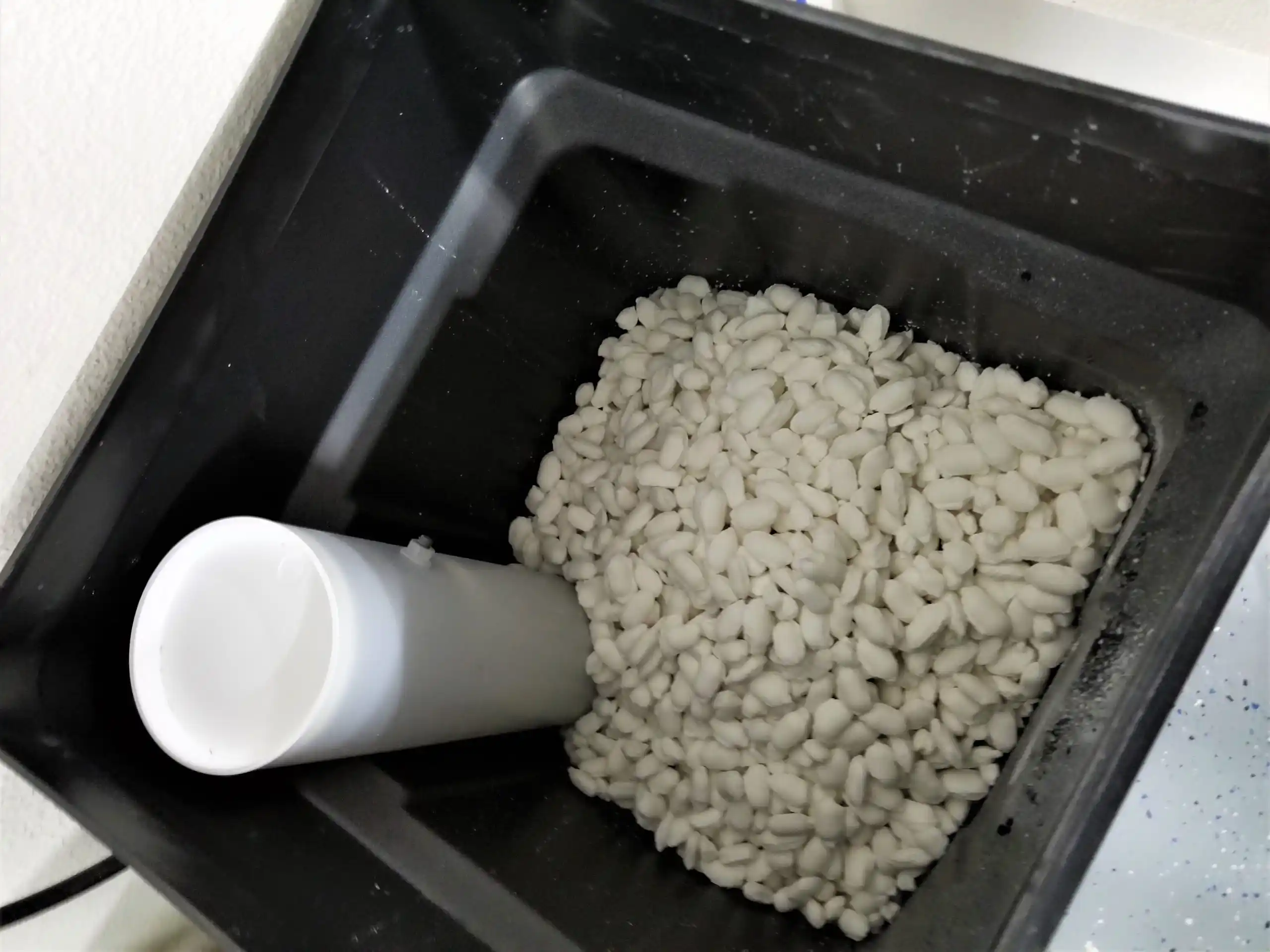 White beans in a black container with a white kitchen tool