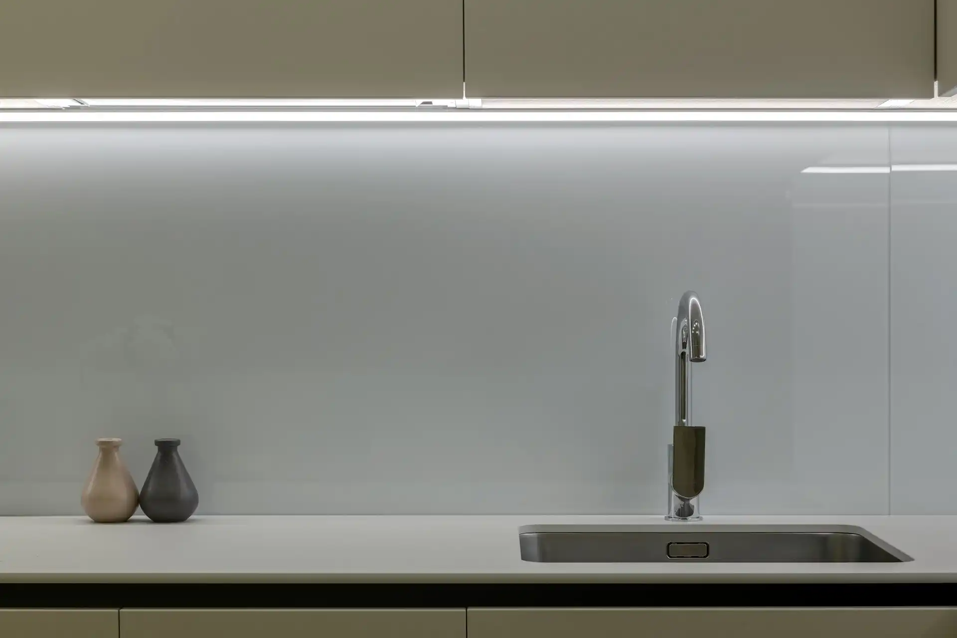 Minimalist kitchen counter with two vases and a modern stainless steel sink