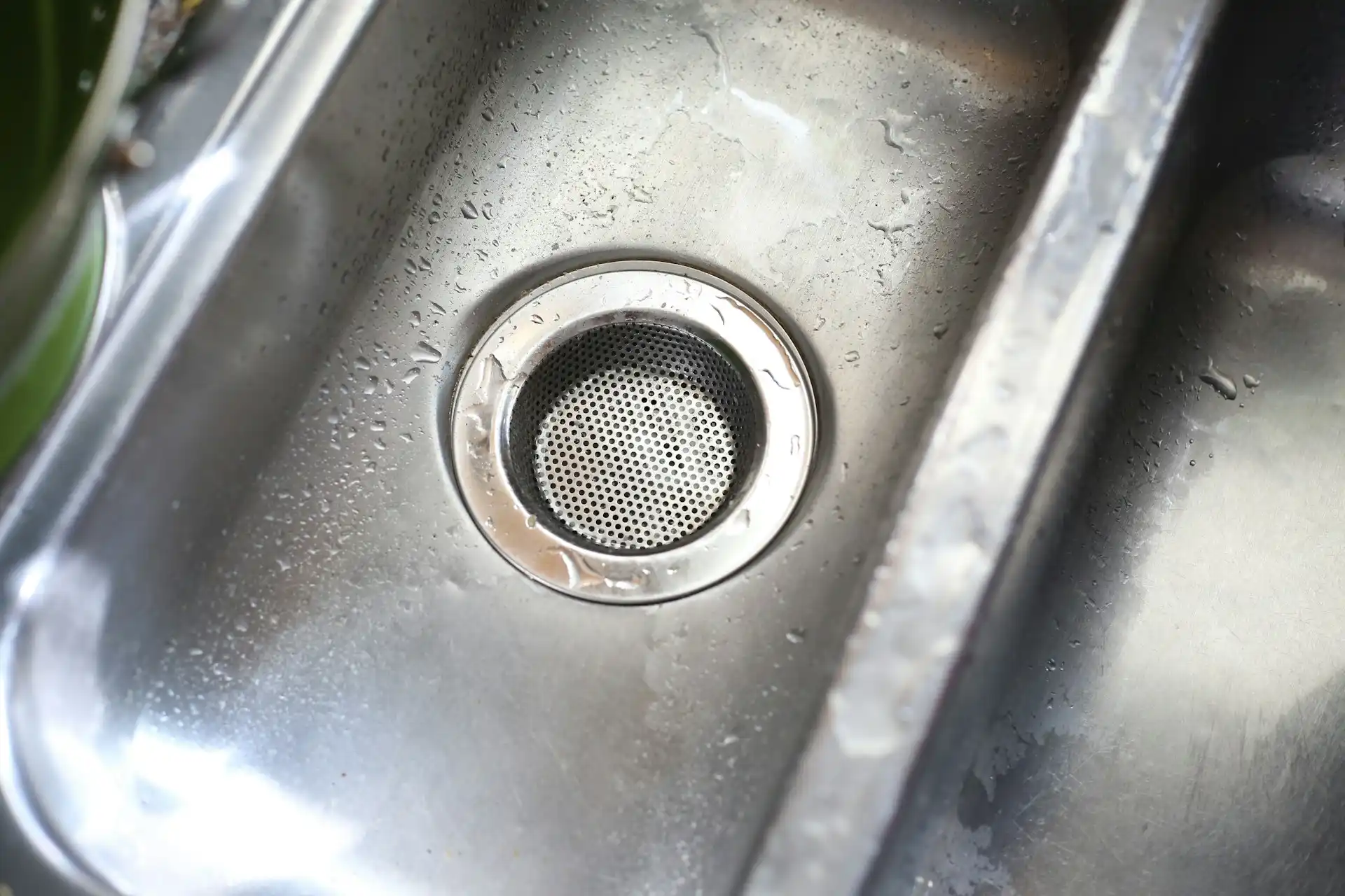 Stainless steel kitchen sink drain with water droplets and perforated strainer
