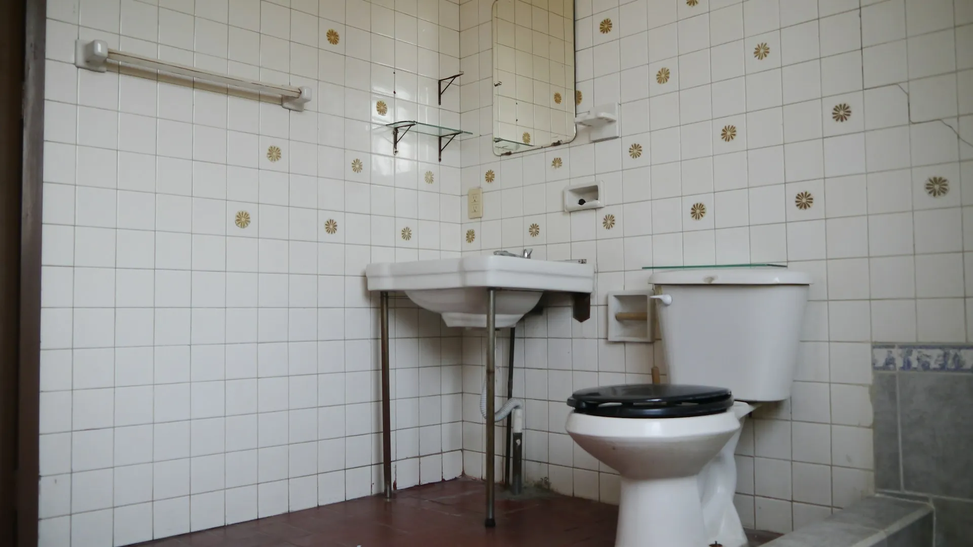 Vintage bathroom with white tiles, floral accents, sink, and toilet