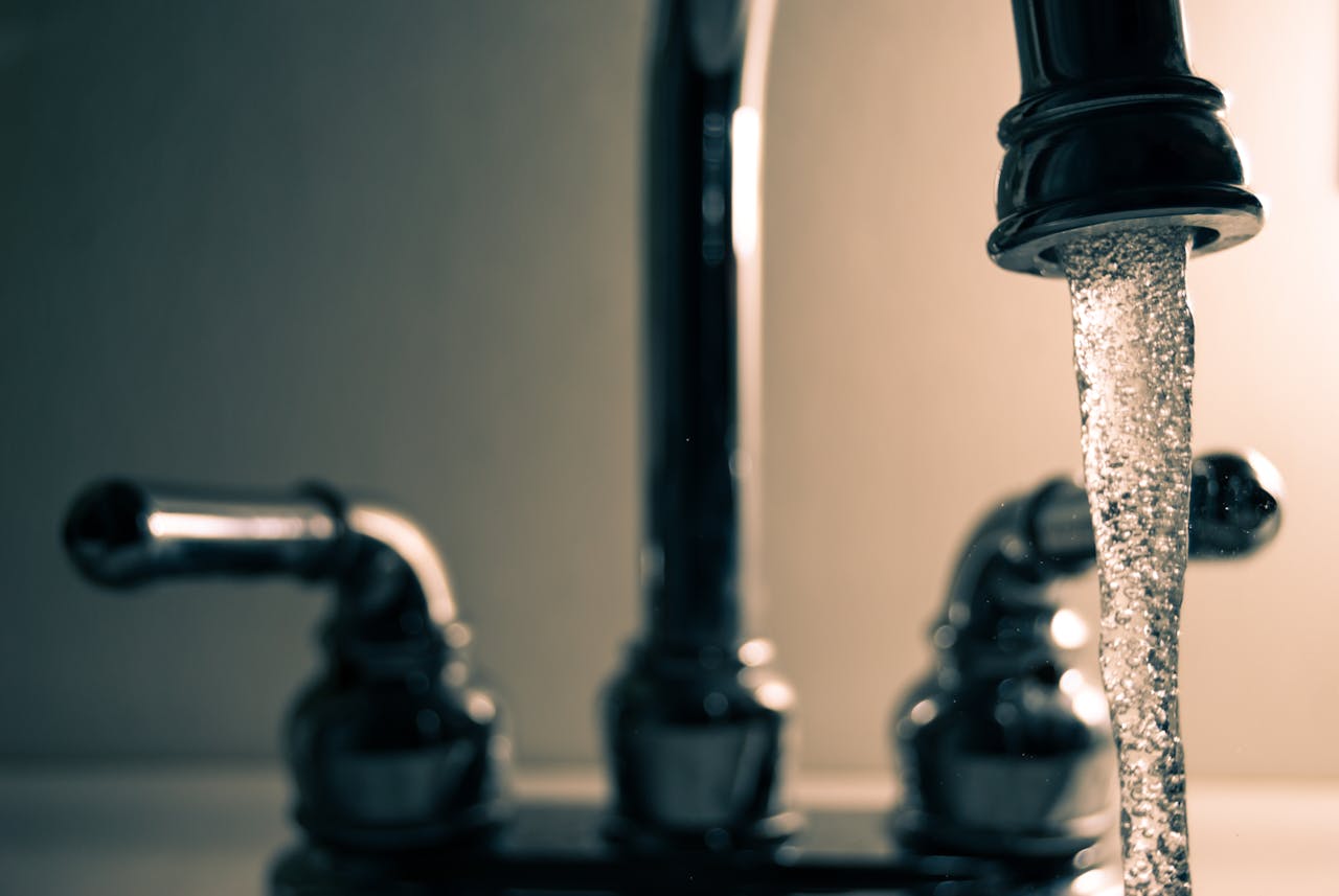 Water flowing from a faucet with blurred bathroom sink in background