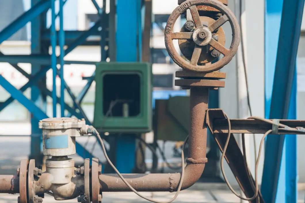 Rusty industrial valves and wheel on blue and green machinery backdrop