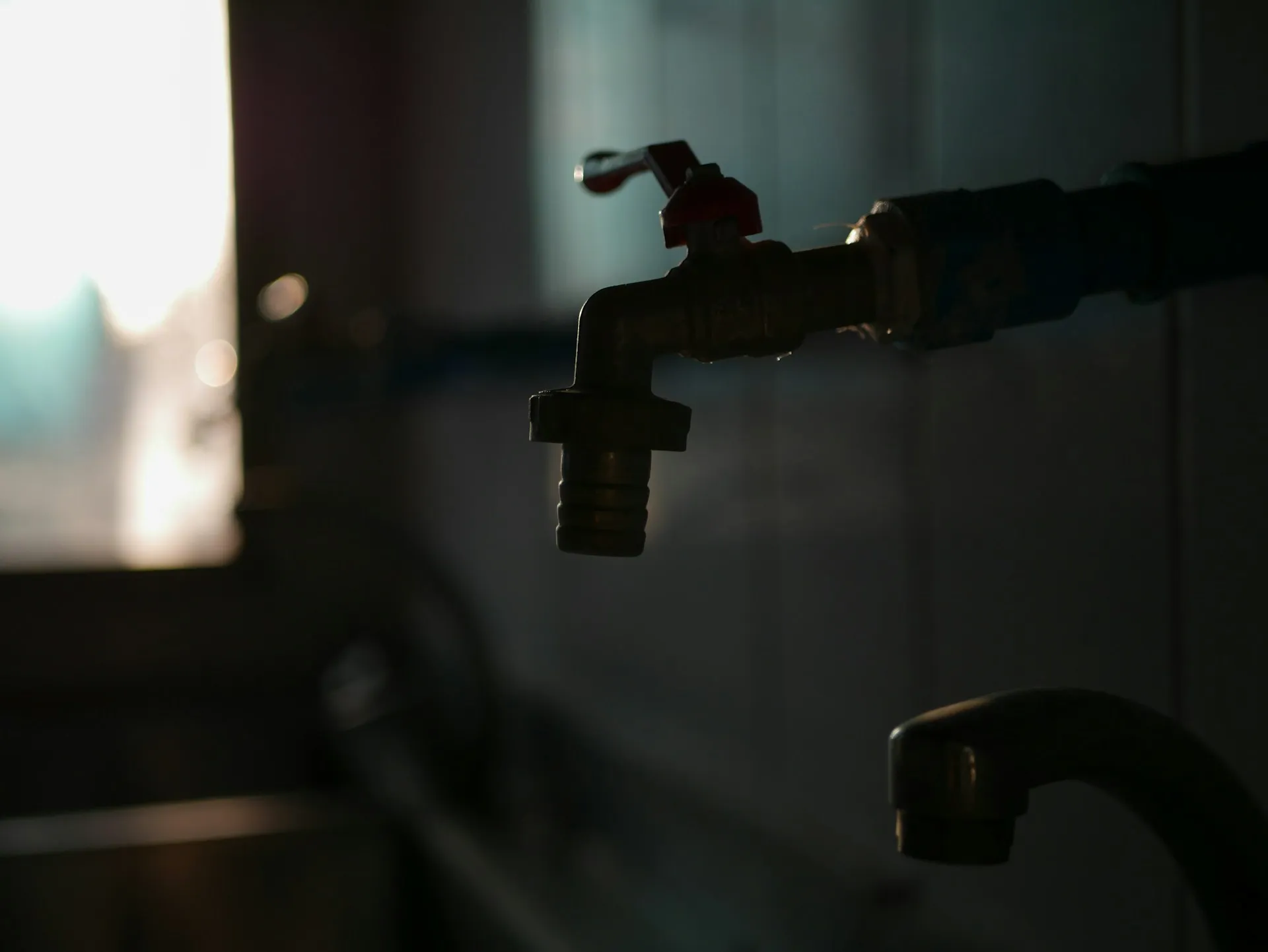 Water faucet in dim light, dripping with metallic valve and blurred background