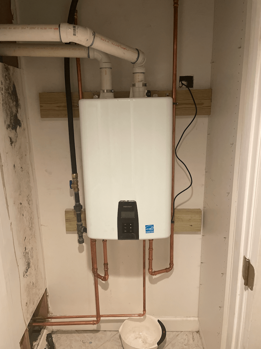 Tankless water heater mounted on wall with copper pipes and connections