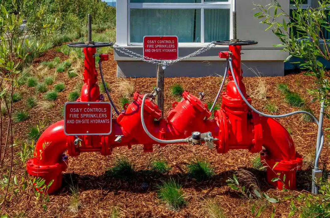 Bright red fire sprinkler system pipes with control valves on mulch bed