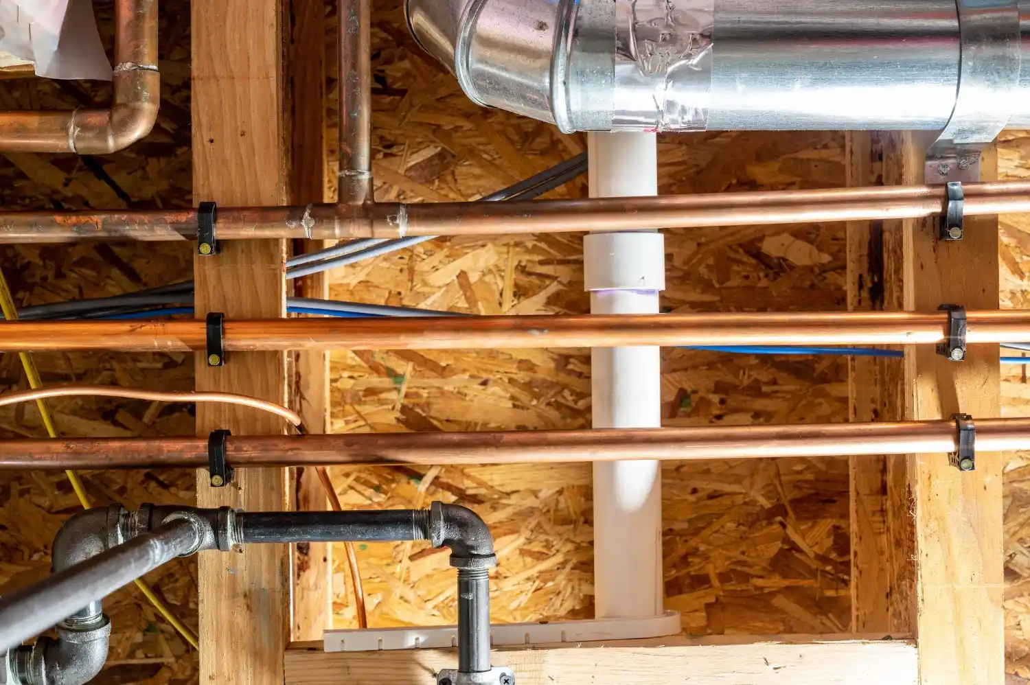 Copper and metal pipes installed in wooden framed building interior