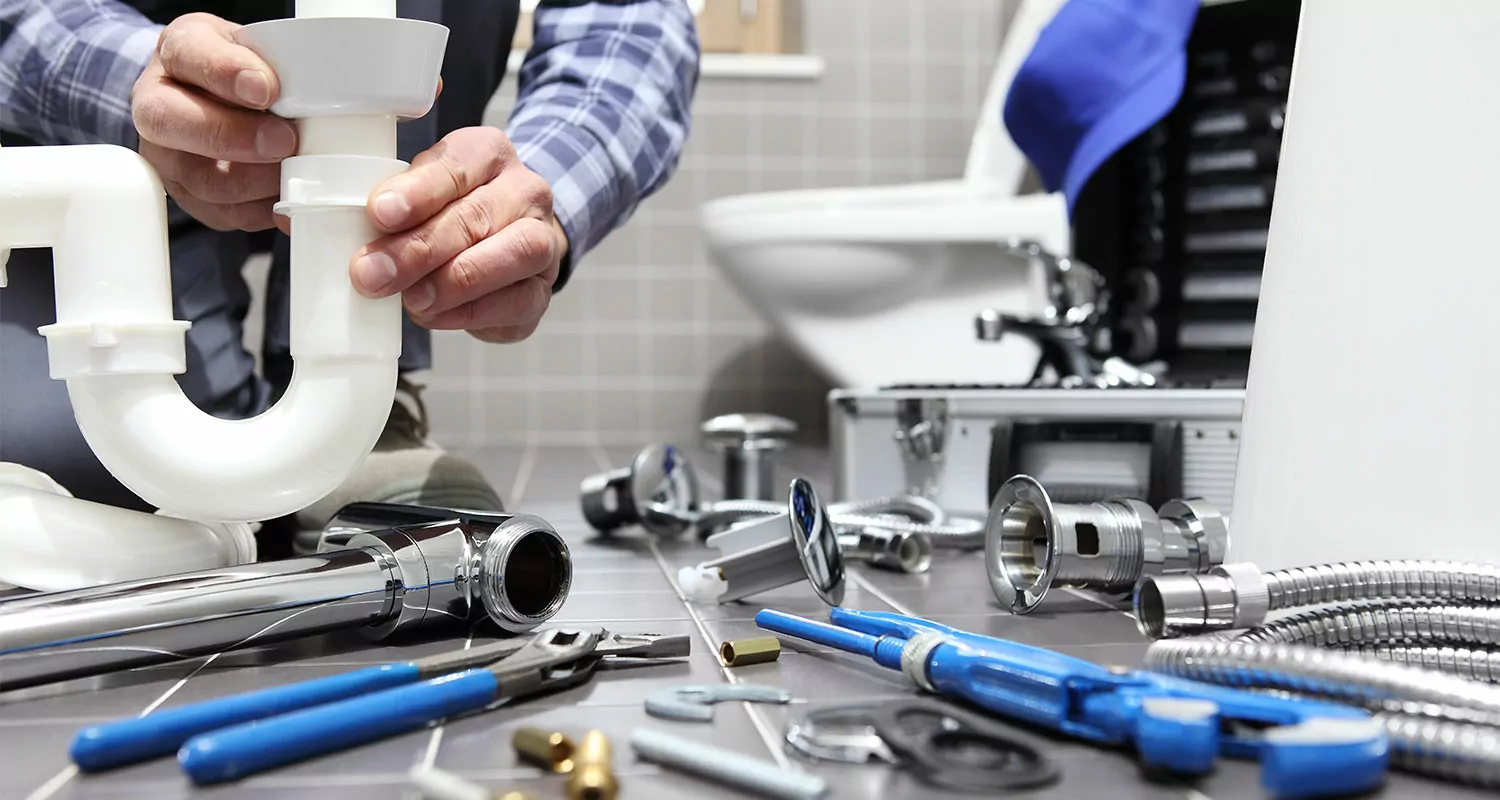Plumber's hands working with pipes and tools on bathroom installation