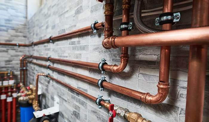 Copper plumbing pipes with valves mounted on a stone wall
