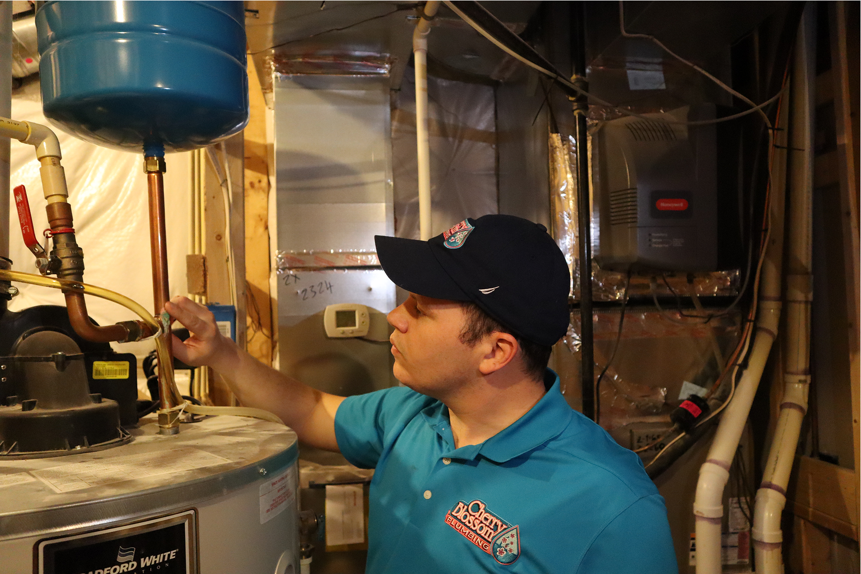 Technician in blue shirt checking water heater in mechanical room