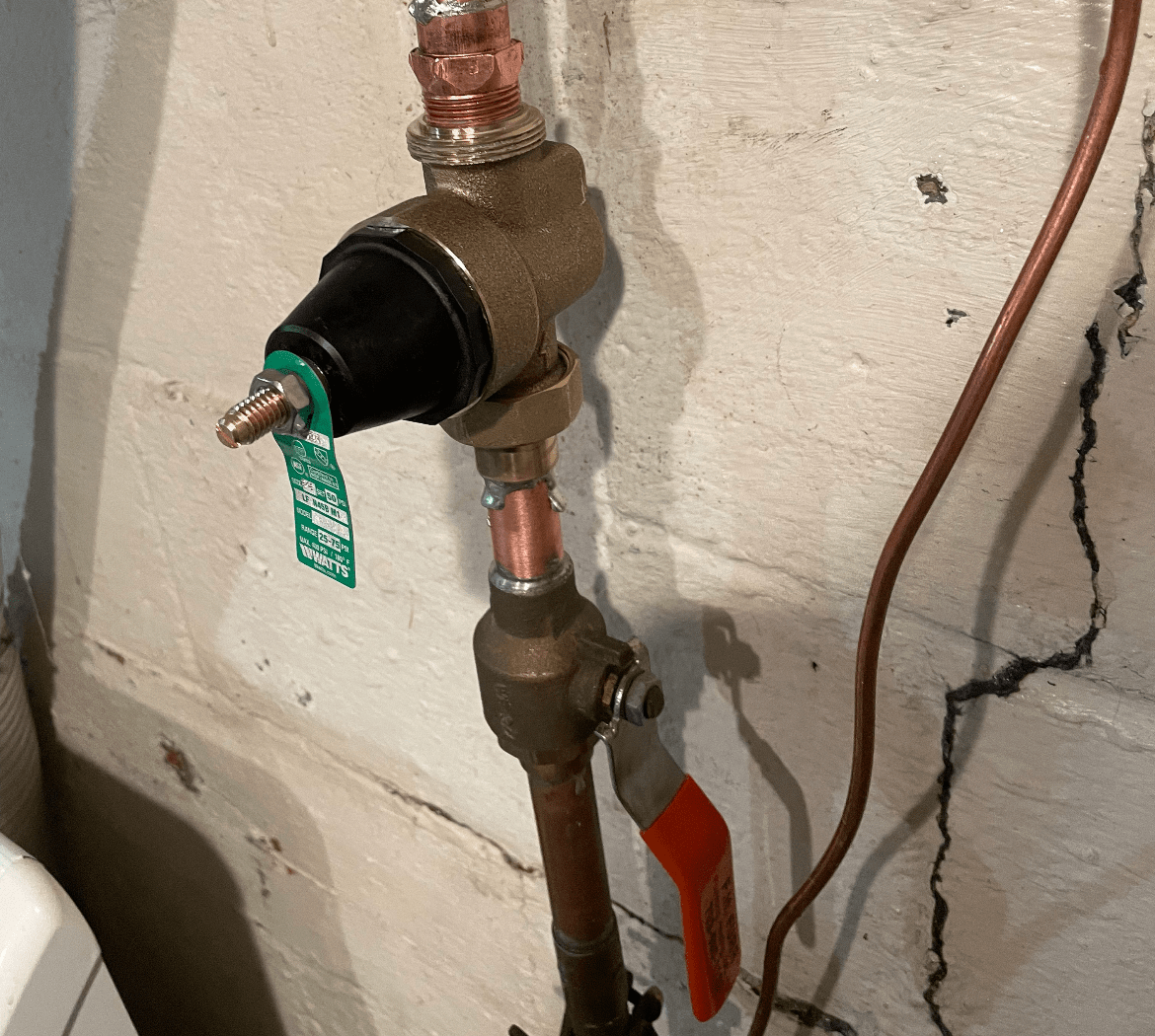 Copper plumbing pipes with valve and green and red tags on wall
