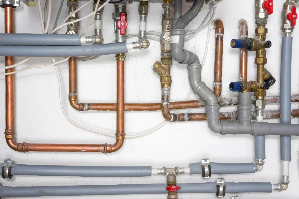 Complex plumbing system with copper and grey pipes, valves, and fittings
