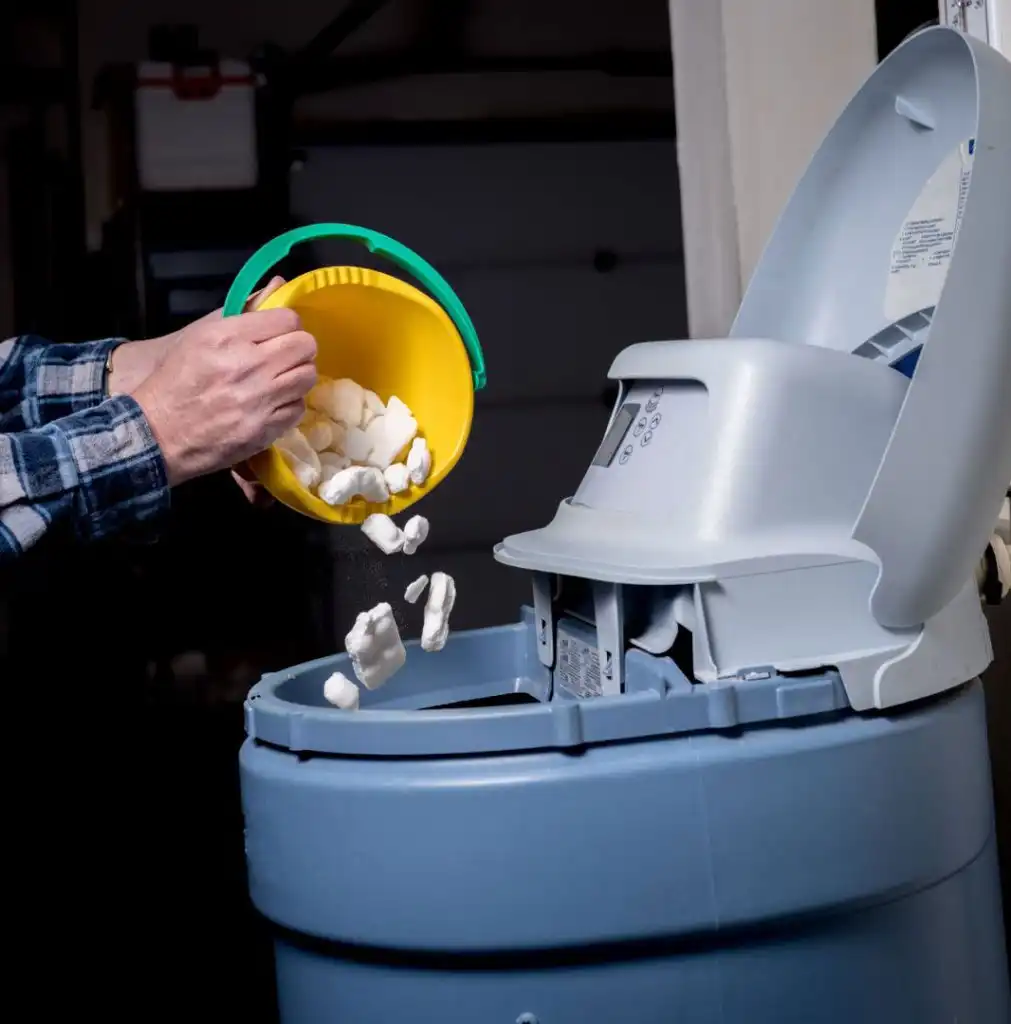 Hand pouring marshmallows into industrial machine with blue container