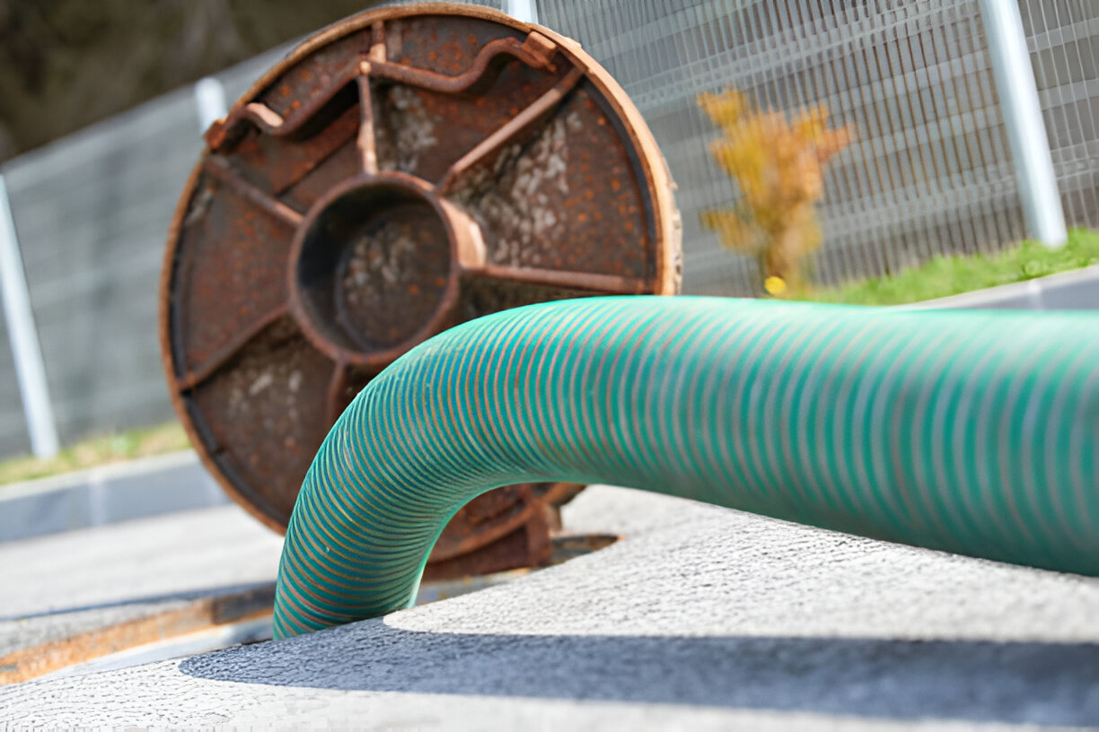 Green corrugated pipe next to rusty metal wheel outdoors