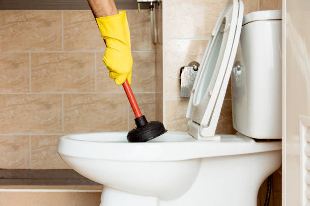 A plumber working on a clogged toilet.