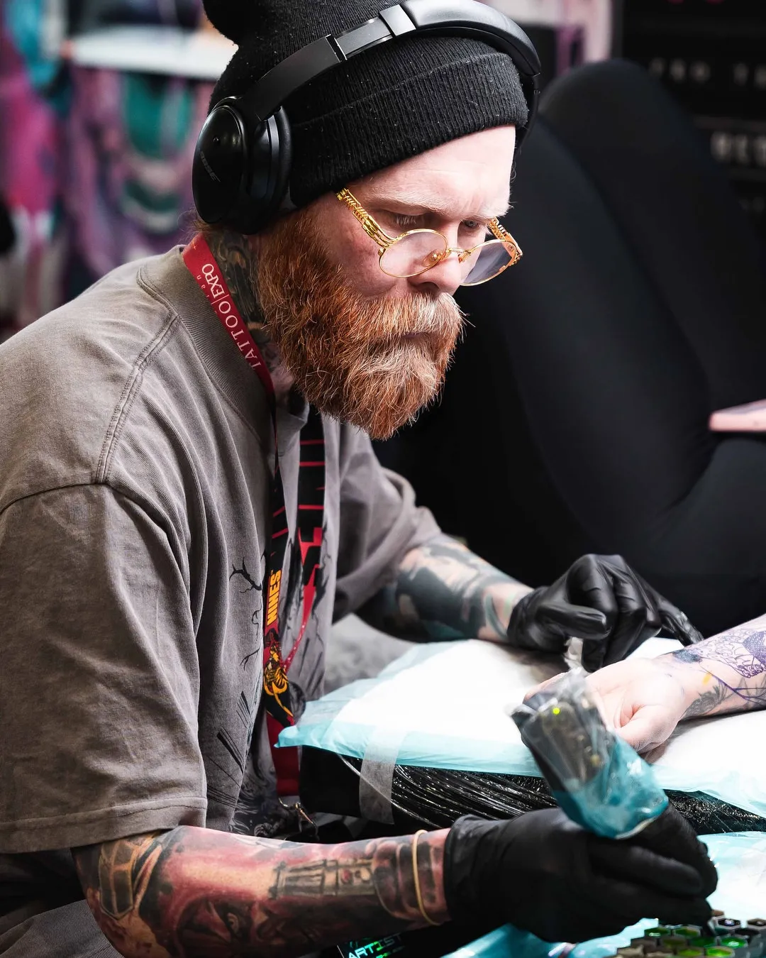 Tattoo artist concentrating while tattooing a client at the Australian Tattoo Expo booth