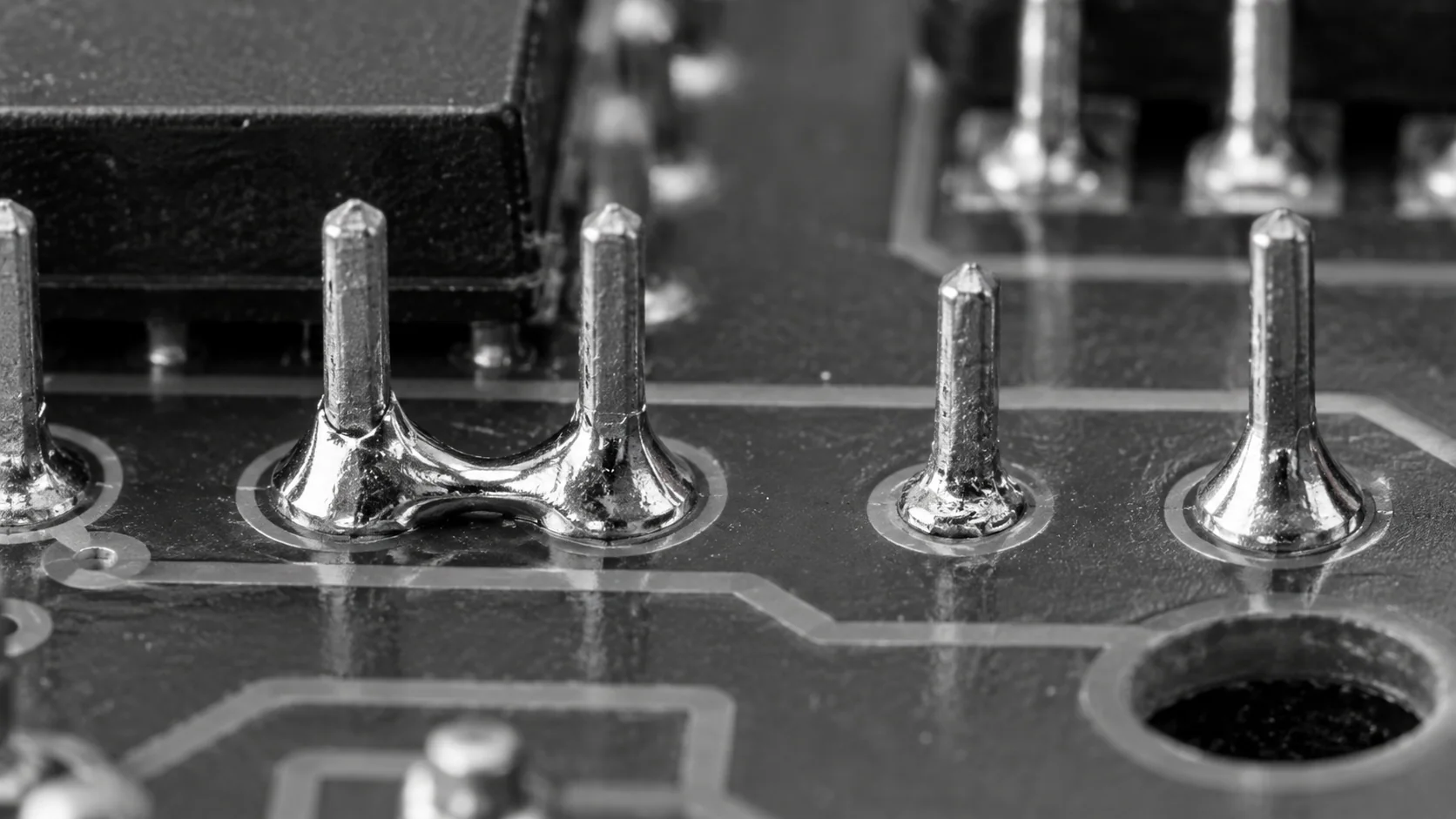 Konzeptionelle Darstellung von Durchsteck-Pins mit einer Lötbrücke und unterschiedlichen Lötmenisken.
