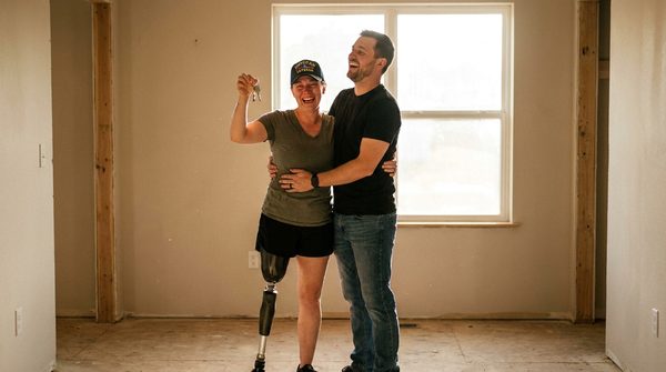 A happy family in front of their new home, illustrating the outcome of a successful VA loan application.