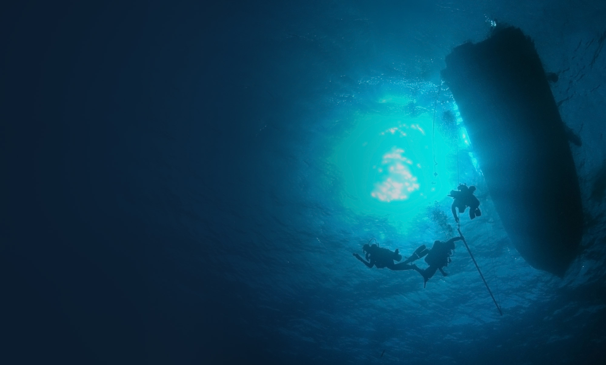 Diver sihouettes against blue ocean surface.