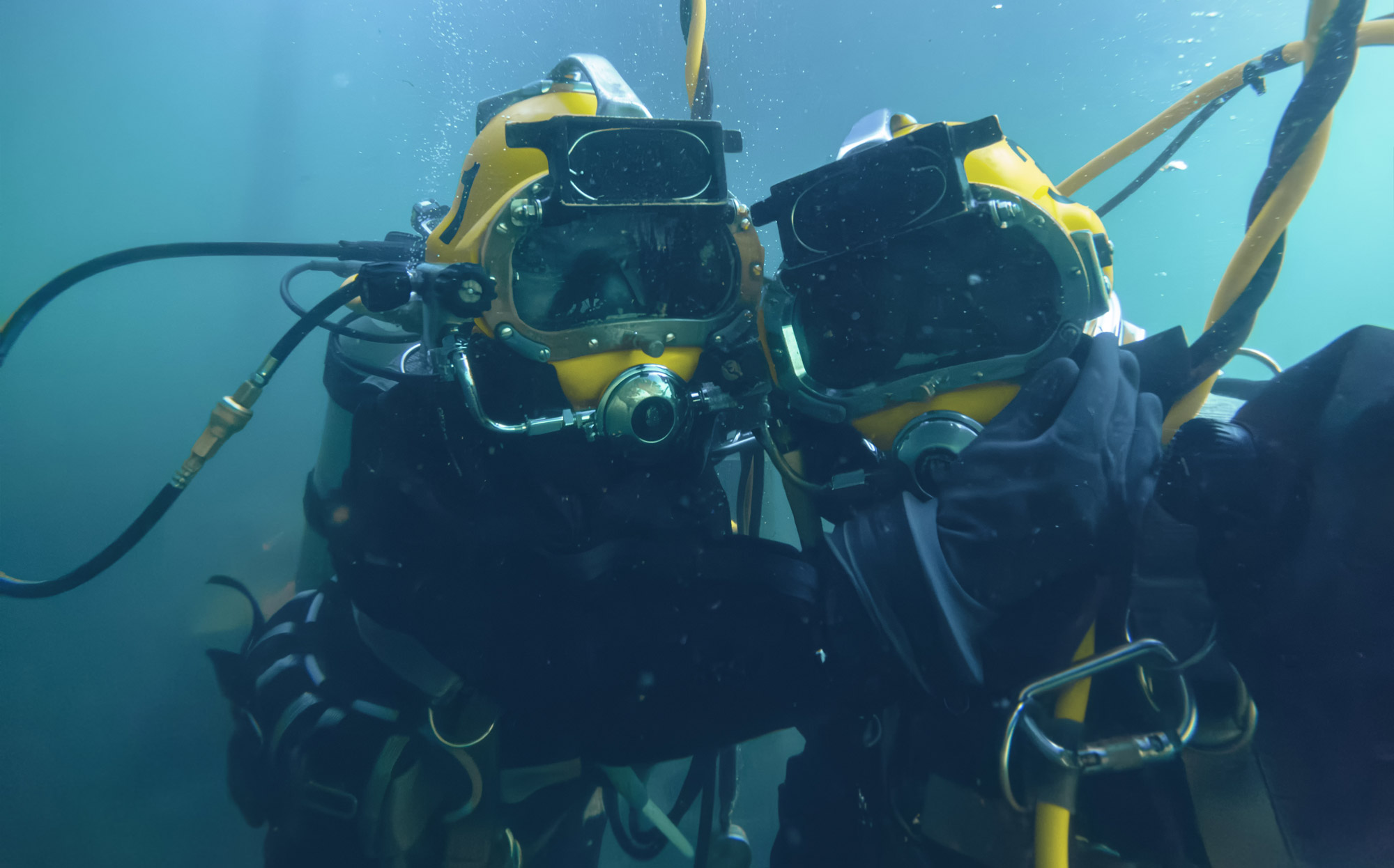Two industrial divers looking at camera underwater